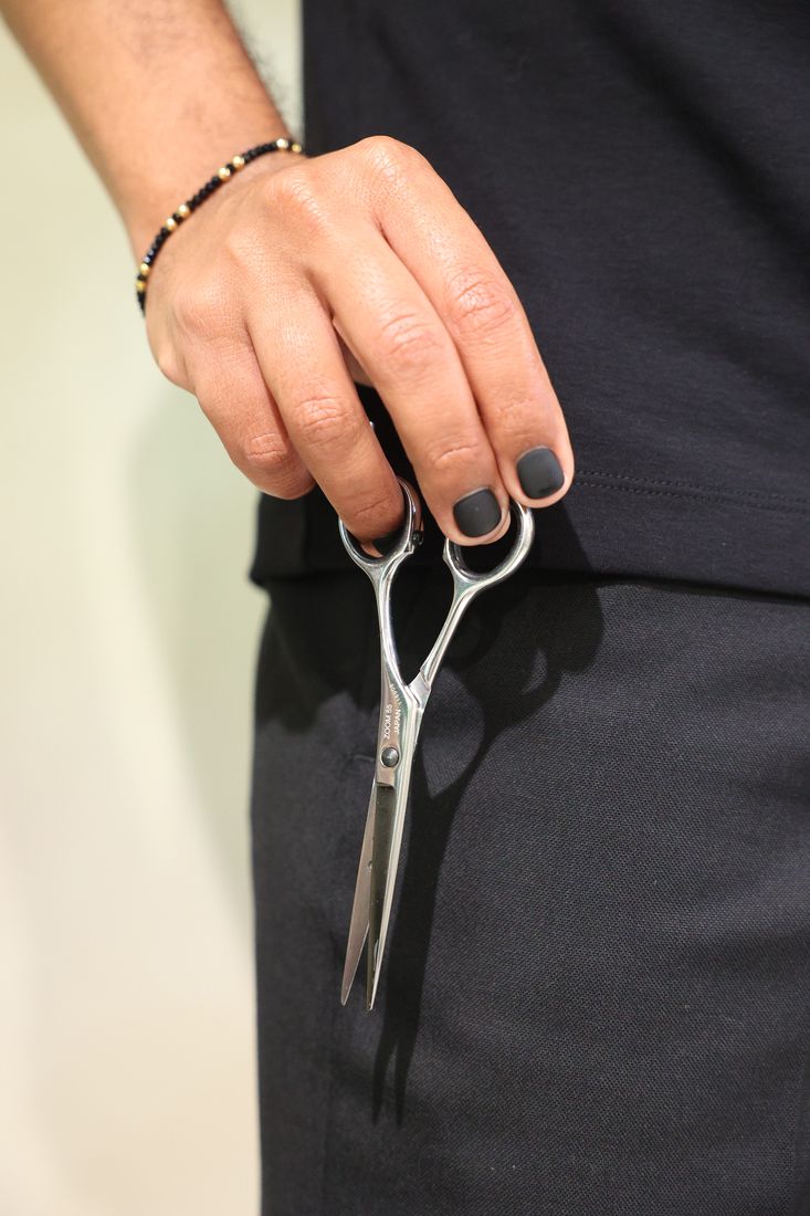 A stylist's hand holding cutting scissors